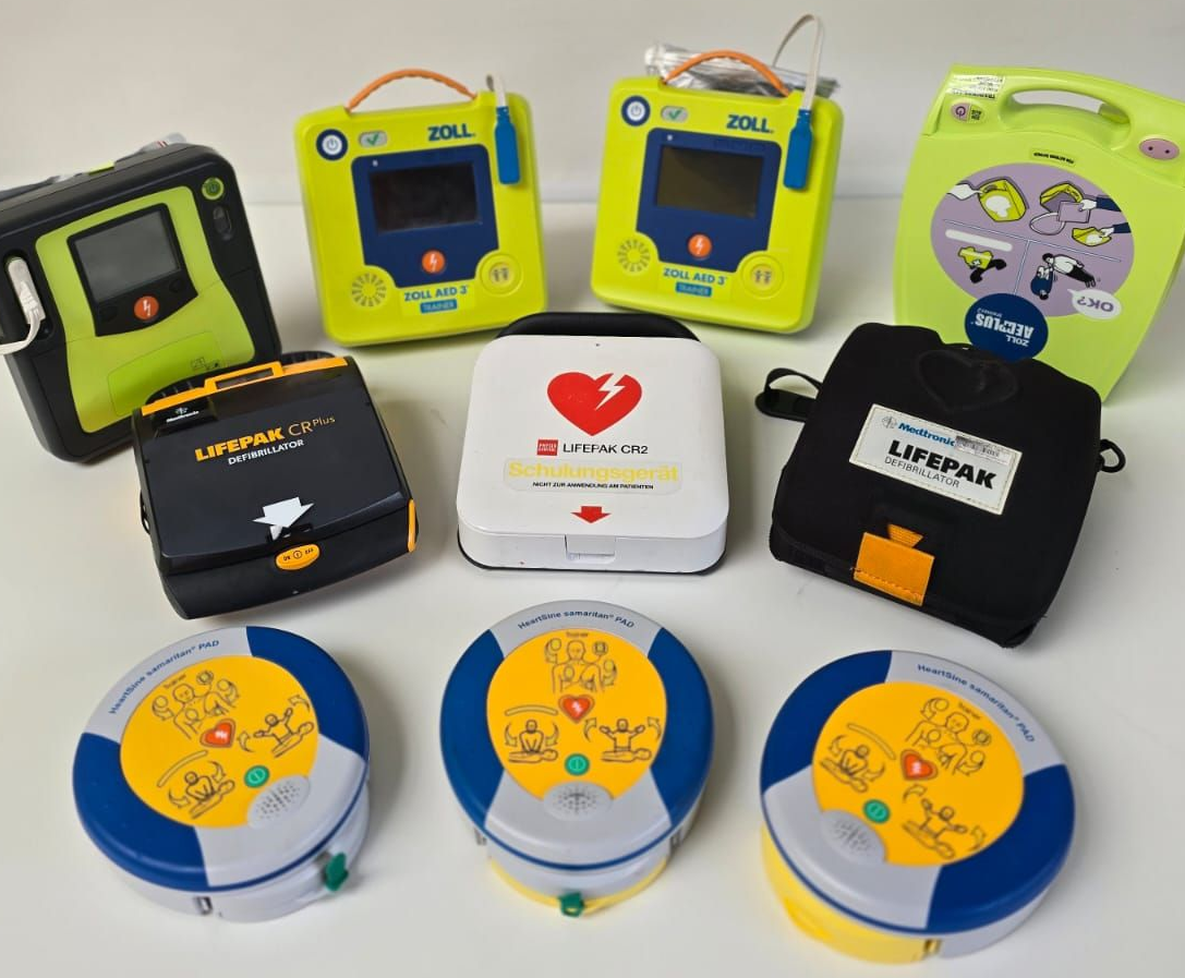 Eine Sammlung verschiedener AED-Geräte, die zusammen ausgestellt sind und unterschiedliche Modelle und Ausführungen für den Notfalleinsatz präsentieren.