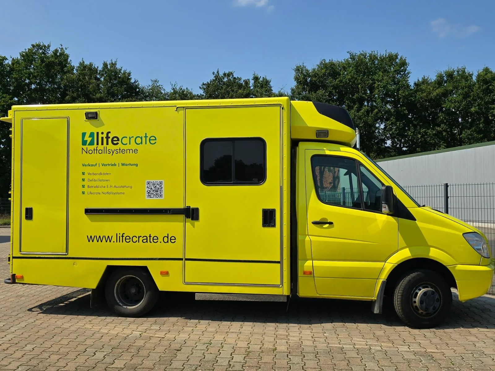 Ein gelber Krankenwagen steht auf einer Ziegelstraße und ist bereit für einen Notfalleinsatz im städtischen Umfeld.